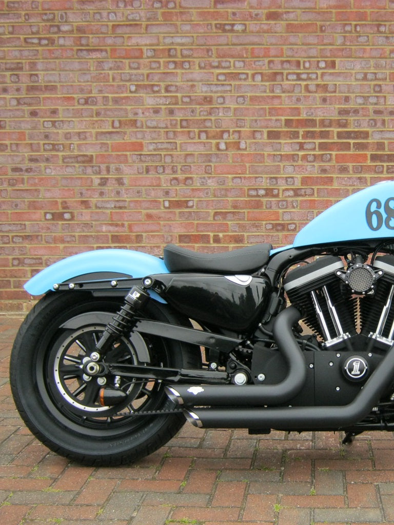 A blue Harley-Davidson Sportster parked in front of a brick wall, equipped with Progressive Suspension 412 Series Shocks 13" Standard 04-22 Sportster.