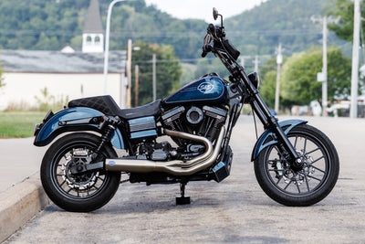 A Brushed Stainless Qualifier 2 into 1 Exhaust System for 2006-2017 Harley Davidson Dyna Models parked on the side of the road, made by S&S Cycle.