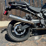 A TC Bros. Profile™ Rear Brake rotor for 2021-up Harley Pan America Models is parked in front of a wooden fence.