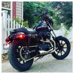 The Sawicki Speed Cannon 2 into 1 Pipe fits '04-'21 Sportster models and includes a stainless steel exhaust pipe, mounting bracket, springs, washers, and small hardware pieces arranged on a white background—ideal for upgrading your Sportster’s exhaust system.