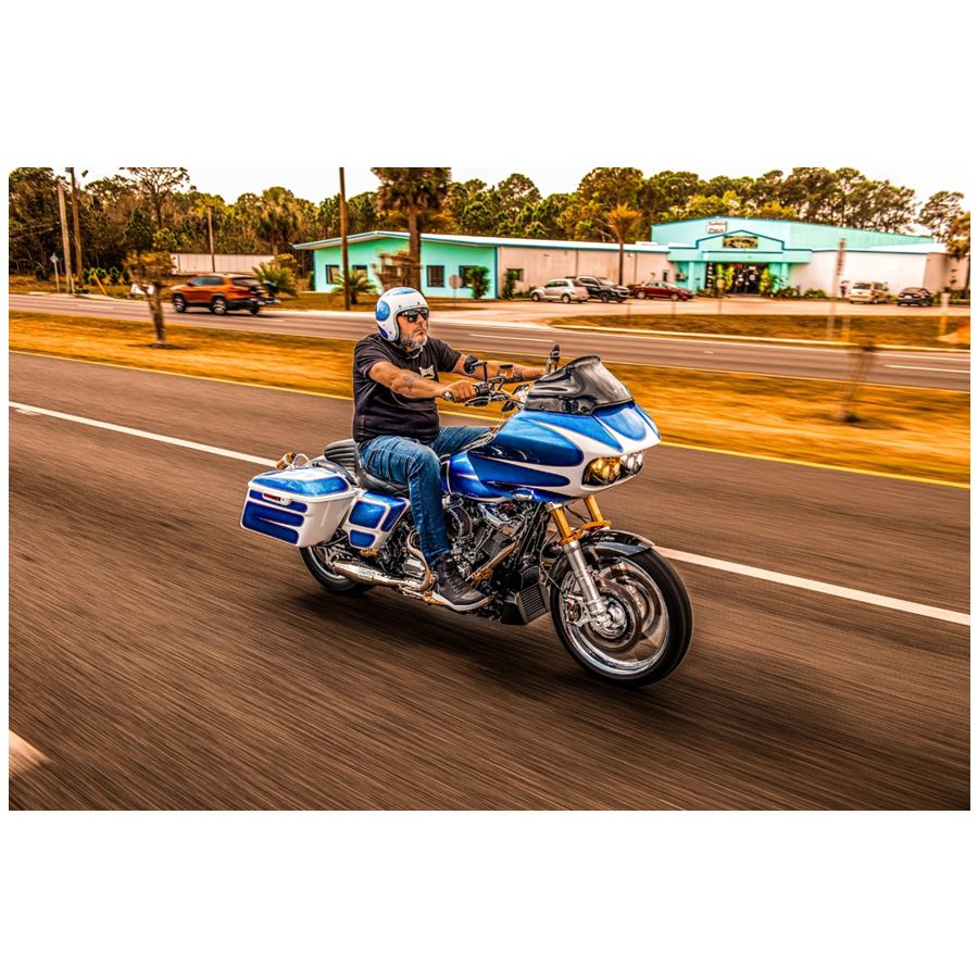 A man riding a Sawicki Speed motorcycle down the road.