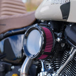 Close-up of a Trask Assault Charge High-Flow Air Cleaner for TBW Harley-Davidson Twin Cam, by Trask, featuring a black metal housing and a visible red pleated filter element.