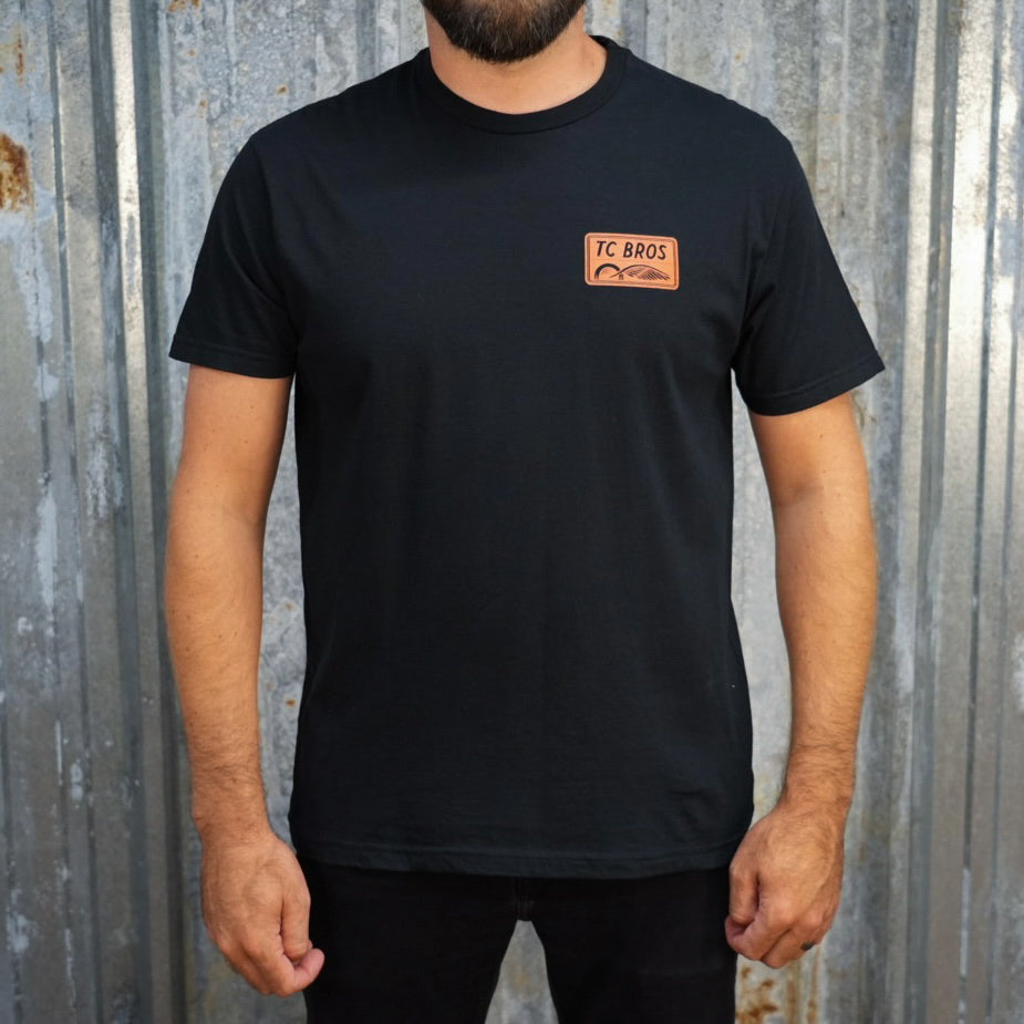 Badge - Black Tee, ring-spun cotton, with a small TC Bros. logo on the left chest area.