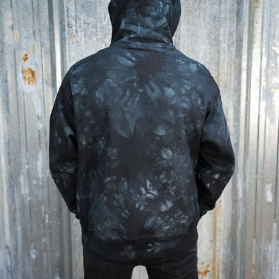 A black and gray camouflage patterned TC Bros. tie-dye hoodie with a yellow logo on the left chest.