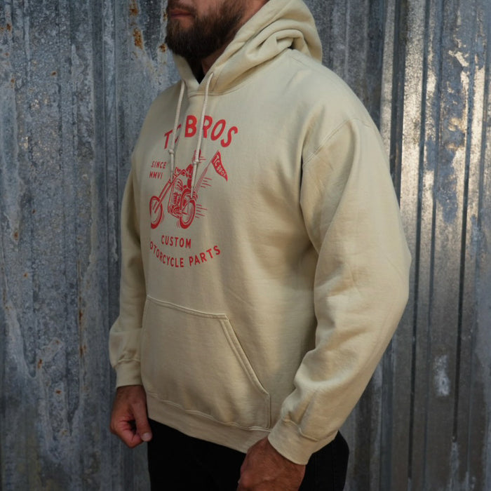 Beige Rider Hoodie - Sand featuring a red graphic of a motorcycle and text advertising TC Bros. custom motorcycle parts, printed on demand.