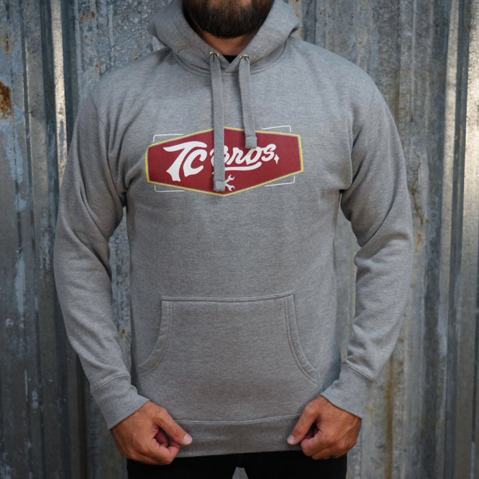 Carbon Gray TC Bros. Shield Hoodie with a red and white "tecos" logo on the front.