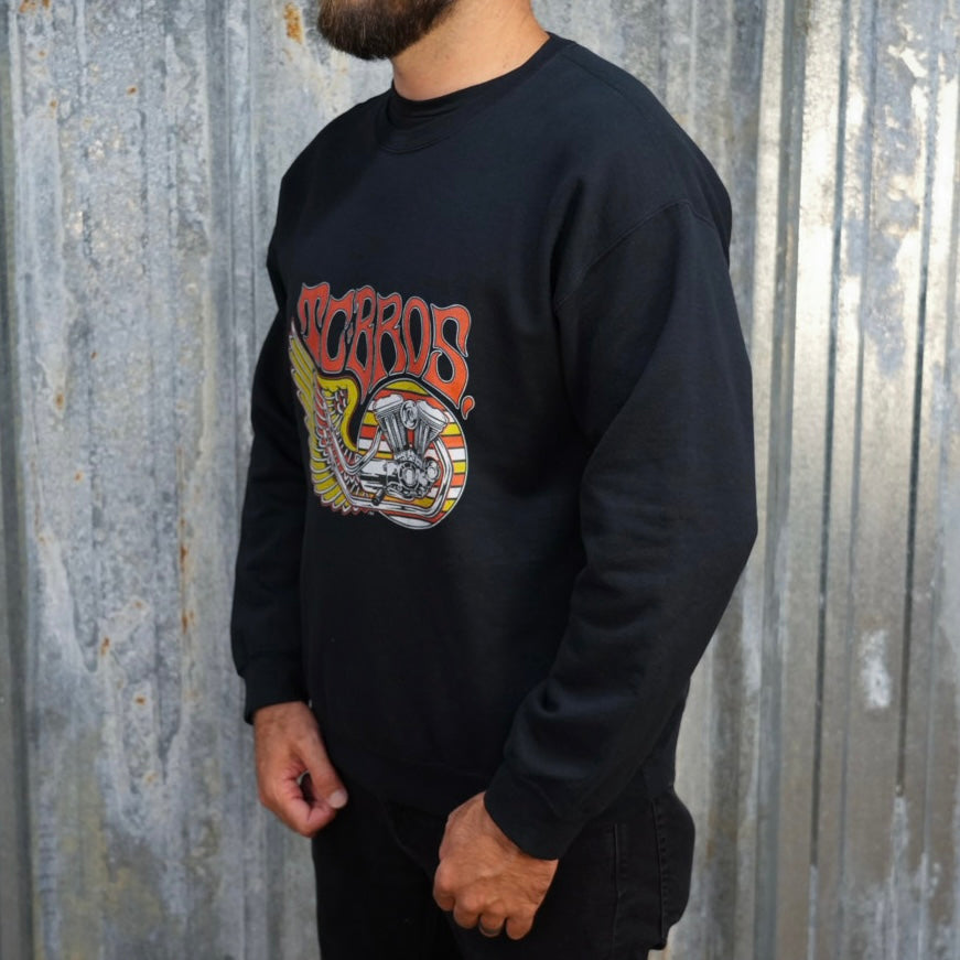 Wing Crewneck Sweatshirt - Black from TC Bros. with a motorcycle-themed graphic design featuring the text "turbos" and an illustration of a winged motorcycle engine. This classic fit sweater ensures warmth and style, printed on demand for