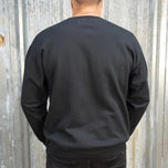 Wing Crewneck Sweatshirt - Black from TC Bros. with a motorcycle-themed graphic design featuring the text "turbos" and an illustration of a winged motorcycle engine. This classic fit sweater ensures warmth and style, printed on demand for