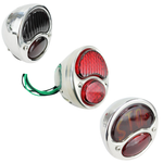 Three TC Bros. Duolamp/Model A Tail Lights: all with chrome housings; one features a black lens, one has red lenses, and one classic Model A style displays "STOP" in red.
