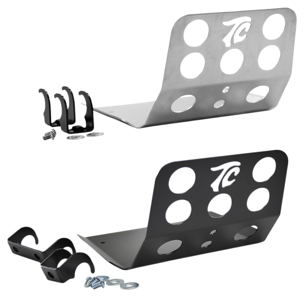 TC Bros. Skid Plate for Harley-Davidson Dyna 1991-2017 features two metal brackets (one silver, one black) with circular cutouts and "TC" logos, including mounting hardware and two black clamps—ideal for skid plate or engine guard setups.