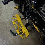 Close-up of TC Bros. Pro Series MX Floorboards for 1984-Up Harley-Davidson Touring, featuring billet aluminum footboards with geometric cutout designs on a concrete floor.