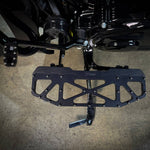Close-up of TC Bros. Pro Series MX Floorboards for 1984-Up Harley-Davidson Touring, featuring billet aluminum footboards with geometric cutout designs on a concrete floor.