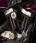 A close-up of a motorcycle engine showcases a Sportster points cover with a red and black emblem. Shiny chrome parts reflect light, highlighting Pangor Cycles' Cheap Sucker Bird Catcher/Air Cleaner for Harley-Davidson Carburetors, against a blurred background for sleek focus.