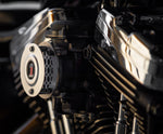 A close-up of a motorcycle engine showcases a Sportster points cover with a red and black emblem. Shiny chrome parts reflect light, highlighting Pangor Cycles' Cheap Sucker Bird Catcher/Air Cleaner for Harley-Davidson Carburetors, against a blurred background for sleek focus.
