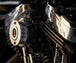 A close-up of a motorcycle engine showcases a Sportster points cover with a red and black emblem. Shiny chrome parts reflect light, highlighting Pangor Cycles&