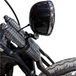 Two TC Bros. Springer Headlight Mounting Brackets with screws, washers, and nuts are shown on a white background. A partial view of a TC Bros. Springer Headlight Mounting Bracket and a motorcycle handlebar mirror appear in the lower right corner.
