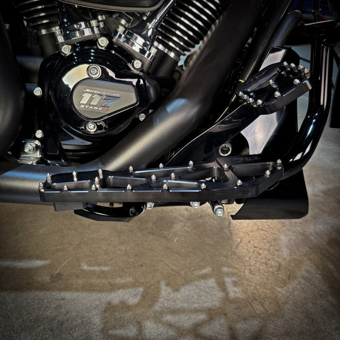 TC Bros. Pro Series MX Slim Floorboards for Harley Davidson Bagger Touring Models feature a skeletal design with metal pins, resembling high-performance pedals in silver, black, and gold. Arranged diagonally, they offer a striking visual appeal.