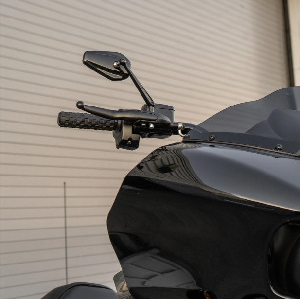 A black motorcycle, Arlen Ness Mini Stocker Forged Mirror - Left, is parked in front of a garage.