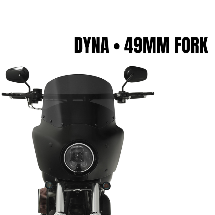 Front view of a black Harley-Davidson Dyna (2006-2017, 49mm fork) with round headlight, side mirrors, and a Memphis Shades Road Warrior Fairing Kit with tinted windshield, shown against a white background.