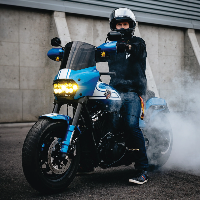 Front view of a black Harley-Davidson Fat Bob (2018-2023) with windshield, mirrors, and orange turn signals. Large "M8 FAT BOB" text above. Enhance wind protection with the Memphis Shades Road Warrior Fairing by Memphis Shades.