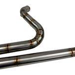 In a workshop with polished metal exhaust pipes, a worker, and an American flag above, the SP Concepts Works Edition Mid Length Elsinore Exhaust for Harley Davidson M8 Touring Bagger 2017-Up is showcased as ideal for enhancing performance.