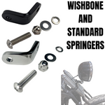 Two TC Bros. Springer Headlight Mounting Brackets with screws, washers, and nuts are shown on a white background. A partial view of a TC Bros. Springer Headlight Mounting Bracket and a motorcycle handlebar mirror appear in the lower right corner.