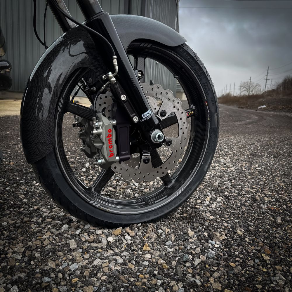 The TC Bros. Pro Series Radial Caliper Brake Line Kit for Harley Touring 2014-2023 includes silver and black bolts, washers, spacers, and two braided hoses with metal connectors, all arranged on a white background. Brand: TC Bros.