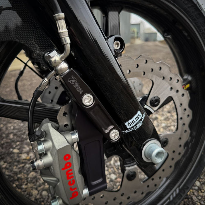 The TC Bros. Pro Series Radial Caliper Brake Line Kit for Harley Touring 2014-2023 includes silver and black bolts, washers, spacers, and two braided hoses with metal connectors, all arranged on a white background. Brand: TC Bros.