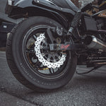 Two TC Bros. motorcycle brake rotors are shown: one is a 12.6" oversized rear floating rotor with a wavy edge for 2000-Up Harley-Davidson wheels, and the other has a smooth circular edge.