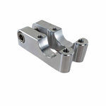 The TC Bros. Gauge Relocation Bracket for Pro Series Modular Risers is a machined metal clamp with two rounded openings and threaded holes, designed for securing gauge brackets to risers.