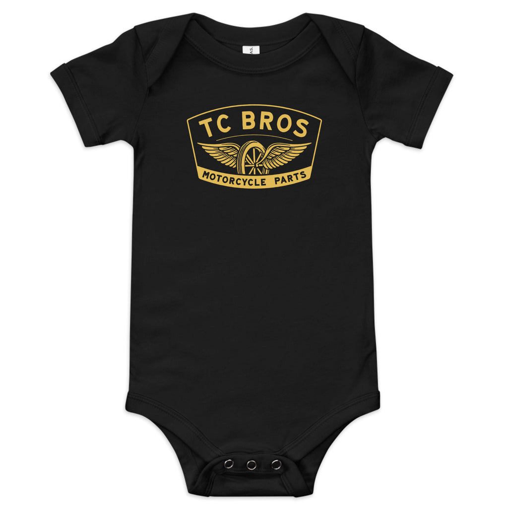 Black cotton Baby Short Sleeve One Piece - Winged Wheel - Black/Gold with three-snap leg closure and TC Bros motorcycle parts logo.