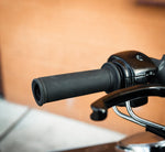 A pair of Speedwell Bear Grips for 7/8" and 1" handlebars, in textured black, are displayed upright before a Speedwell product box on a dark surface.