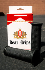A pair of Speedwell Bear Grips for 7/8" and 1" handlebars, in textured black, are displayed upright before a Speedwell product box on a dark surface.