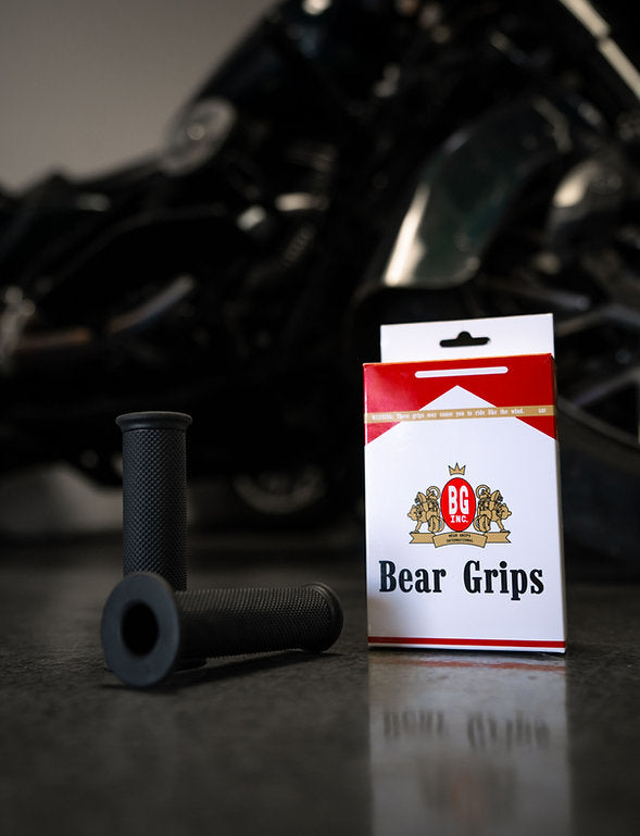 Speedwell grips on a motorcycle handlebars next to a box.