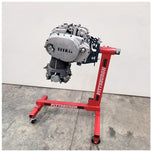 A Yamaha motorcycle engine is securely mounted on a Chop Source Deluxe Yamaha XS650 Engine Stand Brackets by Chop Source, positioned against a plain white wall.