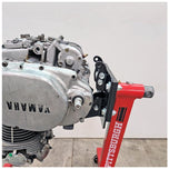 A Yamaha motorcycle engine is securely mounted on a Chop Source Deluxe Yamaha XS650 Engine Stand Brackets by Chop Source, positioned against a plain white wall.