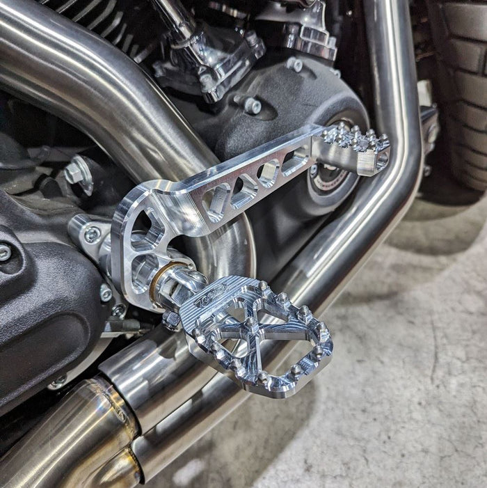 Three TC Bros. Pro Series MX Shifter/Brake Pegs for Harley Davidson, available in silver, black, and gold with multiple spikes, are shown with a metal bolt.