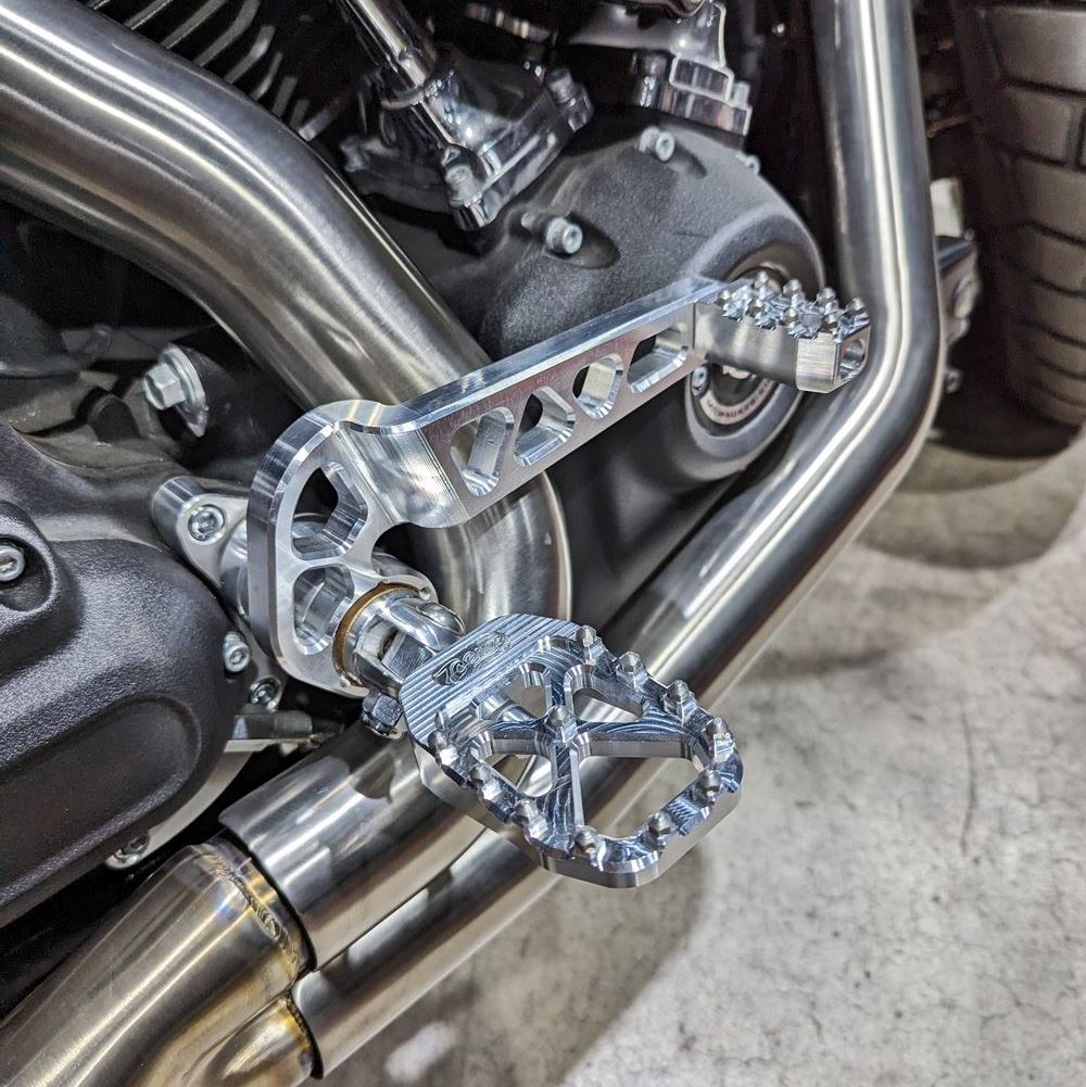 A close up of a motorcycle with a metal foot peg, showcasing high traction and stability for TC Bros. Pro Series MX Shifter Peg for Harley Davidson Models riders.