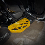 Close-up of a Harley-Davidson Bagger’s left side, featuring black bodywork, engine, and TC Bros. Pro Series MX Passenger Floorboards for 1993-Up Touring models with yellow metal accents on a concrete floor.