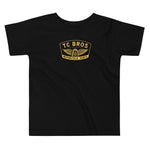 Toddler wearing a TC Bros. Winged Wheel Black/Gold cotton t-shirt, paired with jeans.