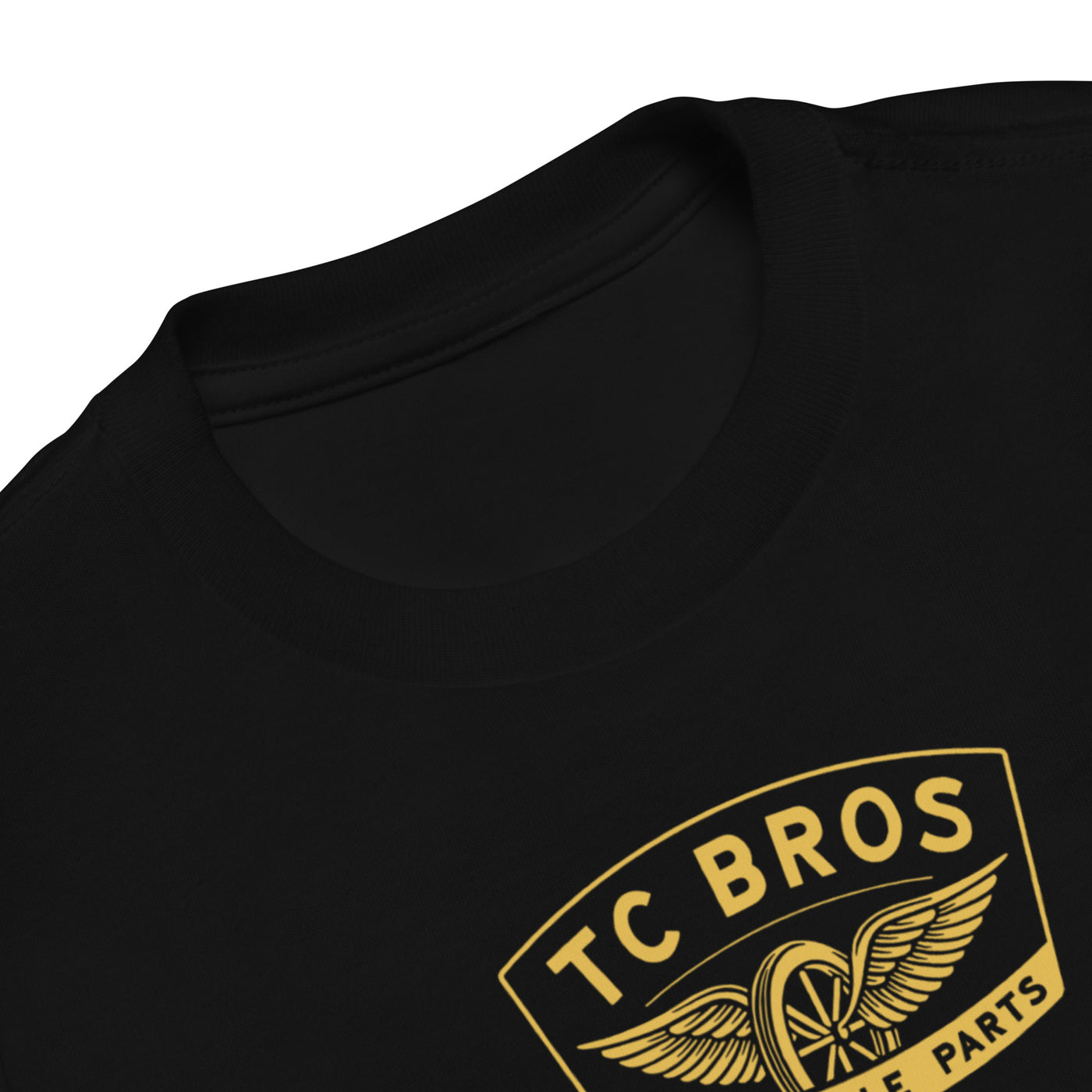 Toddler wearing a TC Bros. Winged Wheel Black/Gold cotton t-shirt, paired with jeans.