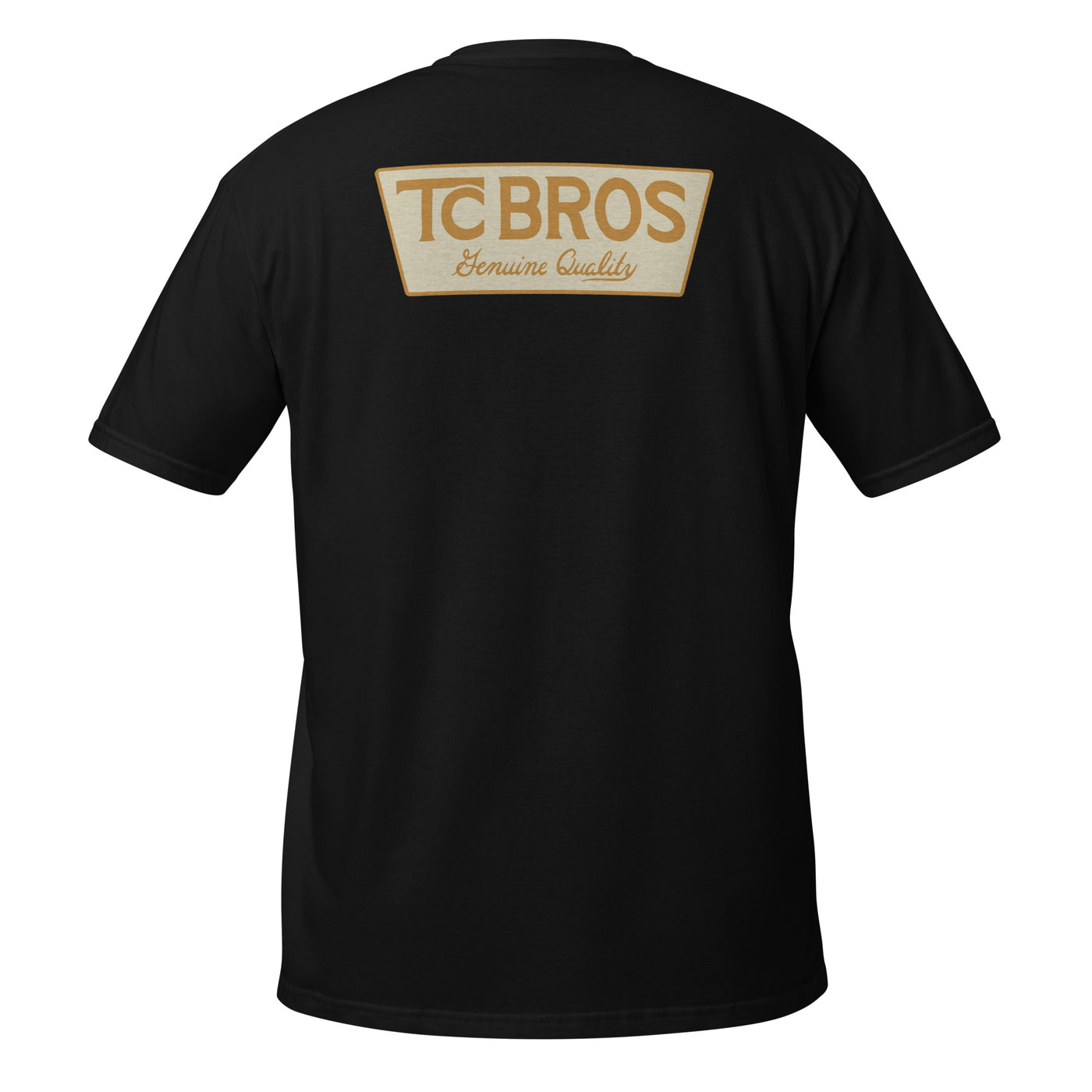 A person wearing the Genuine Quality - Black Tee by TC Bros., crafted from soft and comfy ring-spun cotton, featuring a small logo on the front, stands against a corrugated metal background.