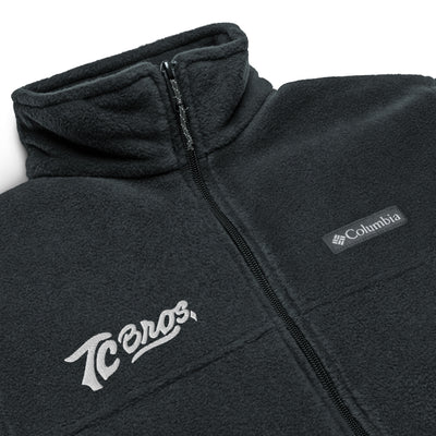 TC Bros. fleece zip jacket - Black with a high collar and zippered front, featuring white embroidered logos on the left chest.