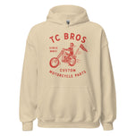 Beige Rider Hoodie - Sand featuring a red graphic of a motorcycle and text advertising TC Bros. custom motorcycle parts, printed on demand.