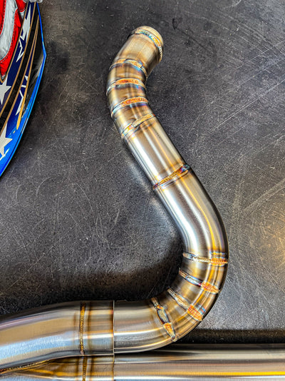 A SP Concepts Works Edition Big Bore Exhaust Dyna 1999-2005 (Stainless) pipe with a helmet on it, featuring the Big Bore Exhaust.