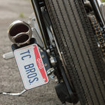 Three TC Bros. Duolamp/Model A Tail Lights: all with chrome housings; one features a black lens, one has red lenses, and one classic Model A style displays "STOP" in red.