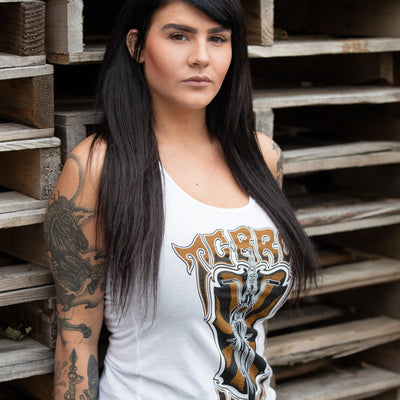 A fitted TC Bros. Women's Trippin' Tank - White, this white tank features a woman with tattoos posing in front of wooden pallets.