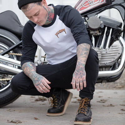 A man with tattoos kneeling next to a TC Bros. Trippin' Raglan - White/Black motorcycle.