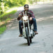 A man riding TC Bros. 1" Rabbit Ears Handlebars - Black Smooth down a country road, gripping the handlebars tightly.