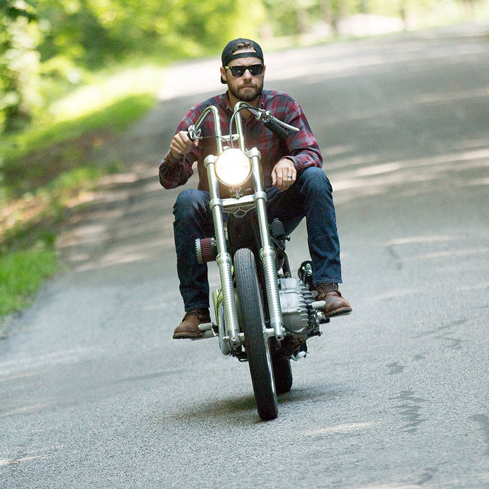 A man riding a motorcycle down a country road on his Avon Speedmaster MarkII 3.00S X 21" Tire Blackwall.